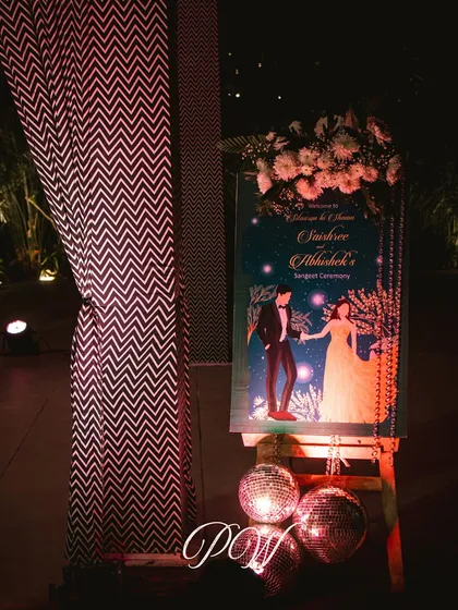 A personalized welcome sign for a Sangeet, featuring a custom illustration of the couple. The disco balls at the base hint at the party to come.