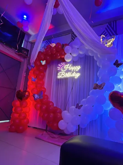 The heart-shaped balloon arch with red and blue mood lighting, creating a romantic and vibrant atmosphere.