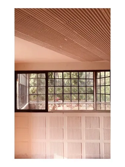 This detail from a farmhouse project emphasizes texture and light. The ribbed ceiling creates a dynamic play of shadows, while the gridded window frames the view of the surrounding nature, demonstrating how material choices can define a space.