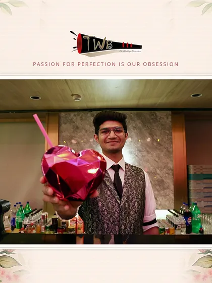 A bartender proudly presents a cocktail in a heart-shaped glass, a perfect touch for a wedding or engagement party.
