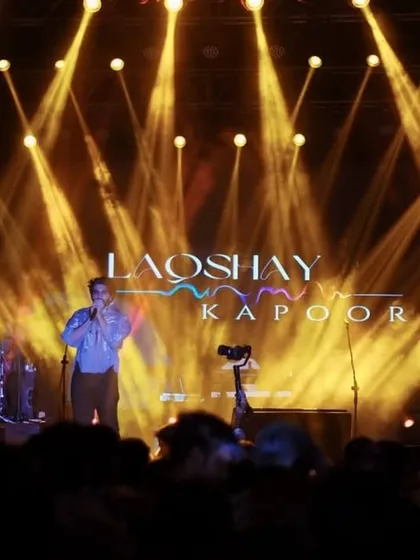 Laqshya Kapoor performing under dramatic golden spotlights at IMS-BHU. This wide shot shows the impressive stage production of a top-tier college festival.
