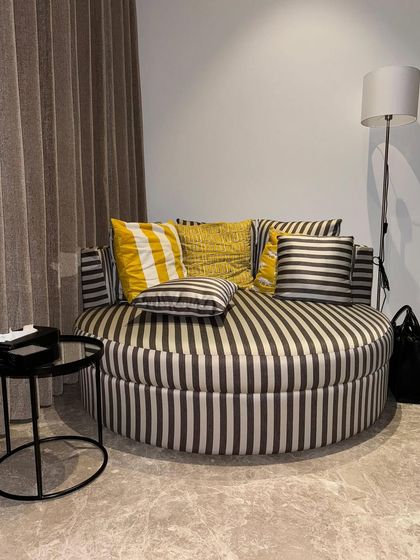 A cozy reading corner we created for a client featuring this oversized, round couch. Upholstered in a bold striped fabric with a pop of yellow from the cushions, it’s the perfect spot to curl up with a good book.