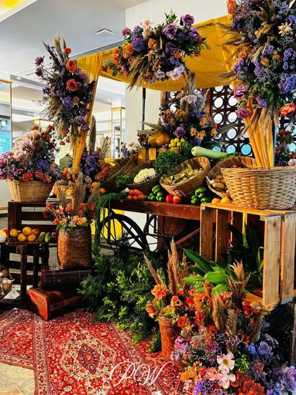 A boho Mehendi setup with a rustic vegetable cart. The cart is overflowing with colorful dried flowers and fresh produce, creating a unique and earthy decor element.