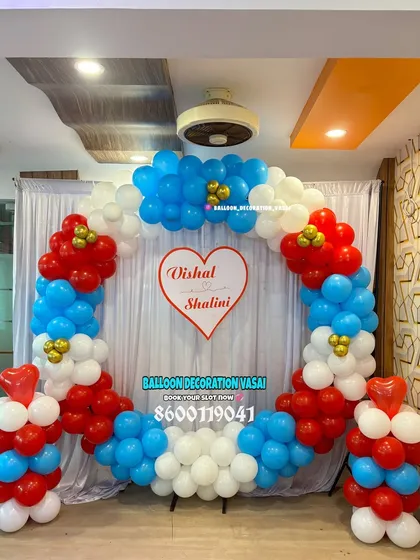 A fun and colorful ring arch made of red, white, and blue balloons. A custom sign with the couple's names, Vishal and Shalini, is placed in the center, making it a personalized backdrop for their event.