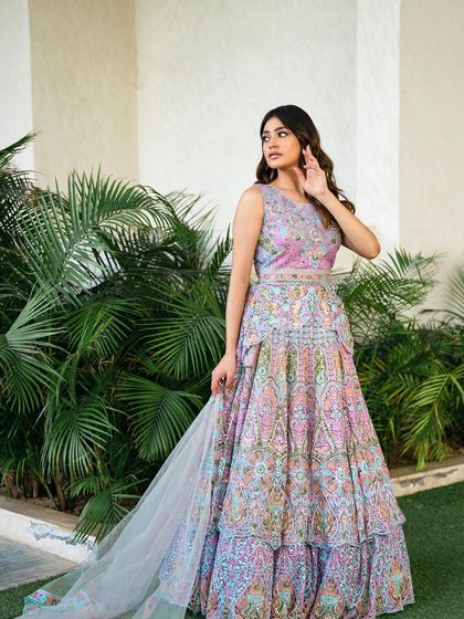 A stunning shot of the ivory peplum lehenga against a green backdrop. The intricate, colorful embroidery stands out beautifully, making it a perfect choice for an outdoor event.
