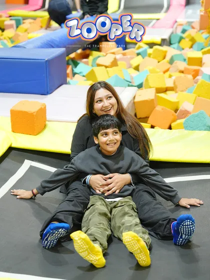 A mother and son share a smile while sitting on a trampoline surrounded by foam blocks. It's all about making memories together.