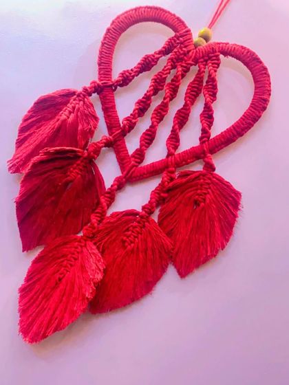 Another angle of the red heart wall hanging, showing the detail of the spiral knots and the delicate, feather-like leaves.