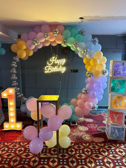 A full view of the pastel rainbow first birthday setup, showing the complete balloon ring and all the decorative elements.