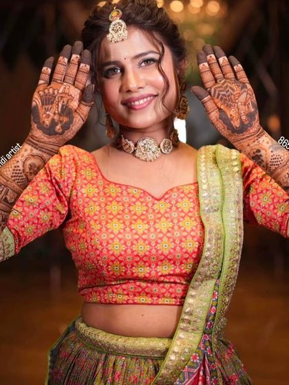 A happy bride with her hands held up to frame her face, showing off the beautiful elephant motifs on her palms.