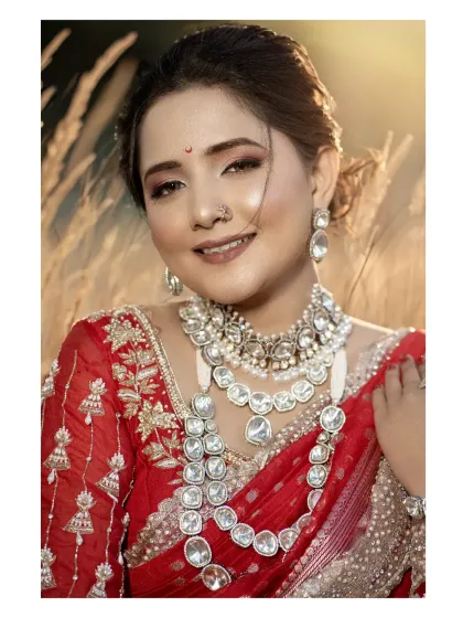 A stunning outdoor bridal portrait. The golden hour light and natural background beautifully complement her red saree and Kundan jewelry.