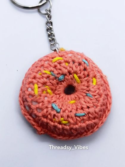 My crochet donut keychain, perfect for adding a sweet touch to your accessories. This shot shows it against a plain background, highlighting its round shape and fun design.