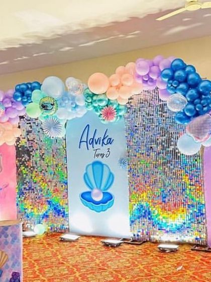 An elaborate mermaid-themed stage with multiple backdrops featuring sea creatures like seahorses and pearls. The blue and purple balloon arch and shimmer walls create an underwater feel.