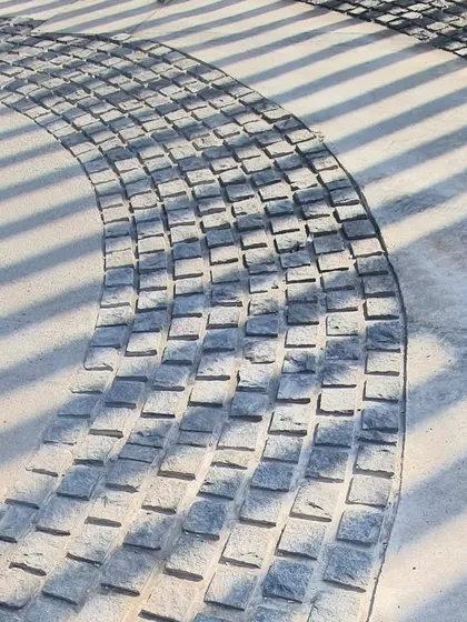 The texture of the hand-laid cobblestones contrasts with the smooth concrete, adding a tactile richness to the ground plane.