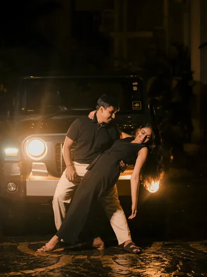 A dramatic night shot where a couple dances in the rain, illuminated only by the headlights of a jeep. This is the kind of moody, cinematic photography we create for couples wanting something bold.