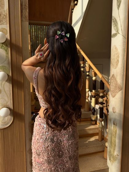 A back view of a model's hair styled in long, flowing waves and a half-up twist, adorned with modern, geometric, multi-colored clips for a pop of fun.