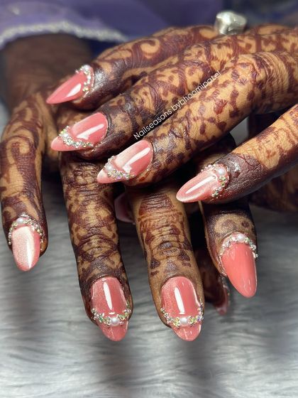 A side view showing the delicate placement of pearls and rhinestones along the cuticle line for a sophisticated finish.