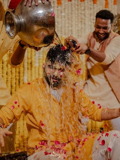 The groom's Haldi gets wild as his friends pour a whole pot of water and petals over him.