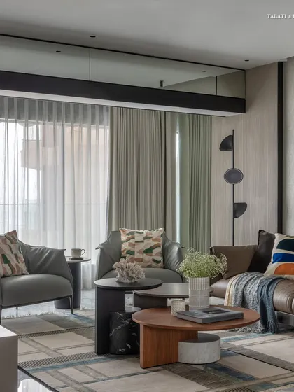 This living room for an art collector blends playful designs with a contemporary minimalist vibe. Custom statement pieces, like the abstract floor lamp and colorful artwork, bring the space to life against the stunning backdrop of Mumbai's sea-facing skyline.