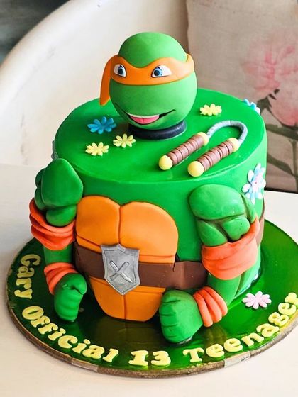 A Teenage Mutant Ninja Turtle cake sculpted to look like Michelangelo, perfect for an "Official 13 Teenager" celebration.