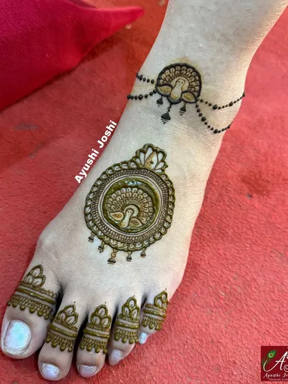 A very minimal and modern foot design, featuring a peacock mandala and a delicate beaded anklet drawn with henna.