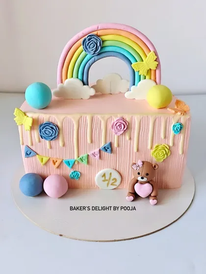 Half the age, double the cuteness! This half-birthday cake is a rectangular design with a pastel rainbow, a sweet fondant teddy bear, and colorful bunting to celebrate the six-month milestone.