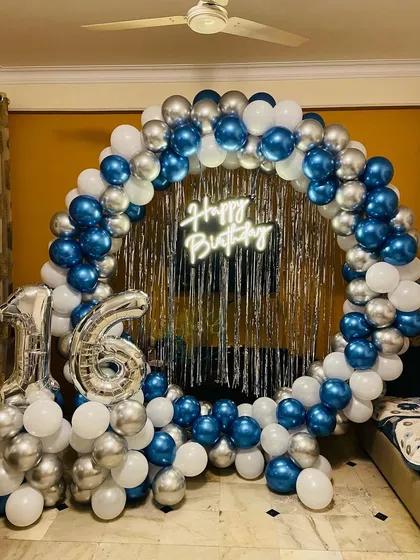 A cool blue and silver theme for a sweet 16th birthday. The setup includes a full ring backdrop with a shimmer curtain, balloons, and large foil number balloons for the age.