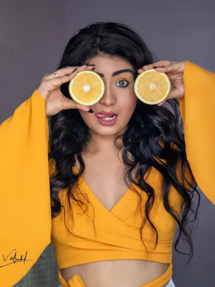 A playful, full-color portrait from our creative series. The model's fun expression and the two bright orange slices create a photo that is bursting with color and energy.