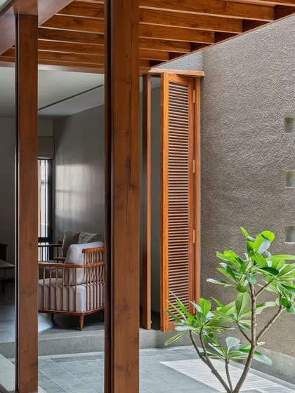 Wooden shutters open from an interior space onto the slender courtyard, allowing for cross-ventilation and a visual link to the home's green spine.