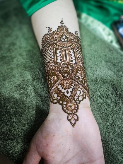 A beautiful jewelry-like cuff design on the back of the wrist, complementing the main henna.