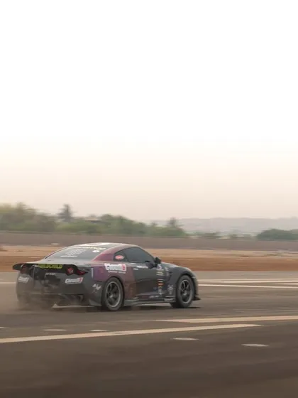 A motion-filled shot from the rear, emphasizing the speed of the Nissan GTR as it powers down the track during an automotive event.