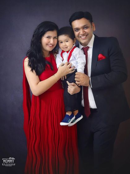 A classic family portrait. Dressed in elegant red and black, this family of three looks picture-perfect in this formal studio photoshoot.