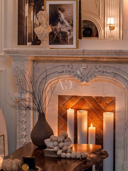 A close-up of the intricately carved marble fireplace mantel. The details, from the classical motifs to the curated objects on top, reflect a commitment to artistry and historical richness.