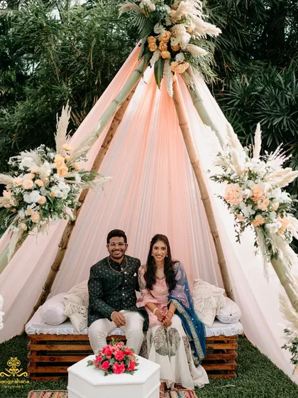 The happy couple seated in their beautiful teepee tent, the centerpiece of their dreamy boho-themed Mehendi.