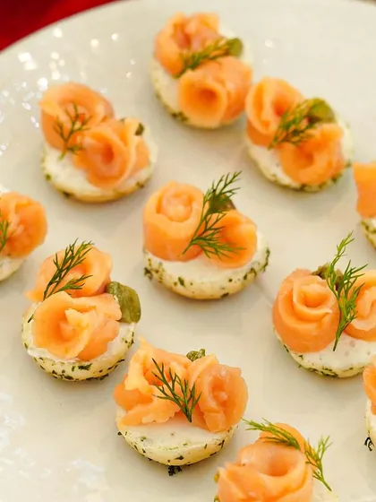 Smoked salmon roses on herb blinis, a classic and elegant canapé. These bites are perfect for Thanksgiving, Christmas, or any sophisticated gathering.