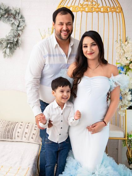 A portrait of serene motherhood. The expectant mother, in a beautiful light blue gown, is surrounded by a delicate floral setup, creating an atmosphere of calm and beauty.