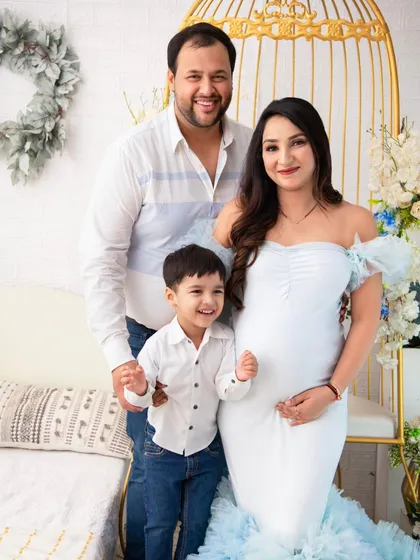 A portrait of serene motherhood. The expectant mother, in a beautiful light blue gown, is surrounded by a delicate floral setup, creating an atmosphere of calm and beauty.