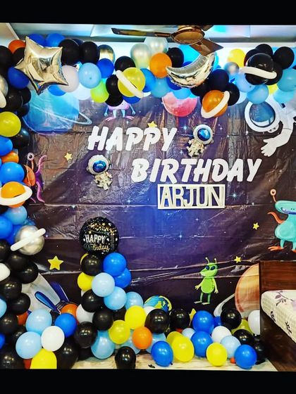 An outer space-themed birthday decoration for a bedroom. The setup includes a galaxy backdrop, planet balloons, and an astronaut, perfect for a young space enthusiast.