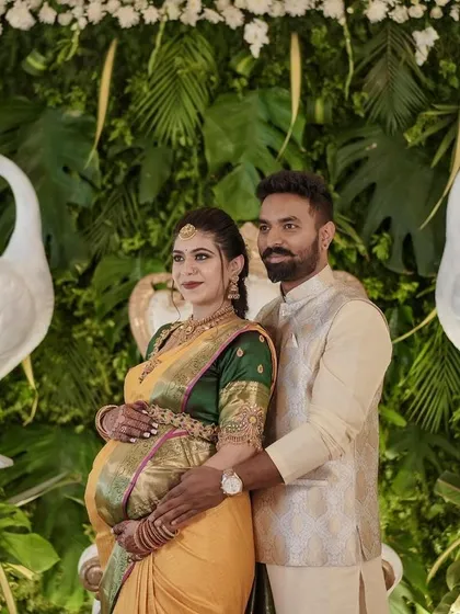 The happy couple posing in front of the decor I designed for their baby shower. The green wall with white peacocks provided a fresh and elegant setting for their celebration.