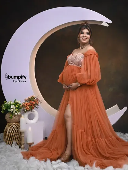 A beautiful solo shot of the mom-to-be standing by the moon prop. Her joyful expression and the magical set create a truly special photograph.
