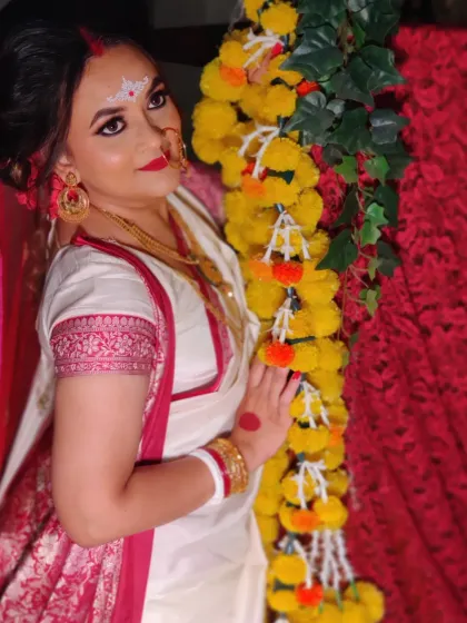Nishita posing against a backdrop of marigold flowers, looking every bit the traditional Bengali bride.