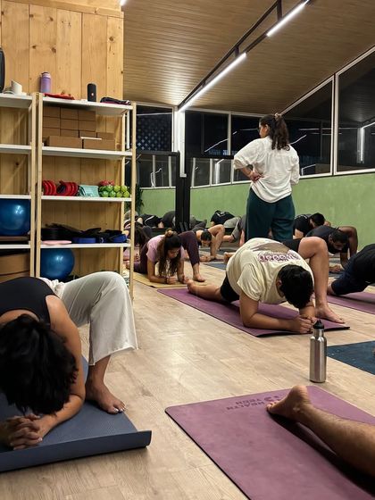 A student in a deep lizard lunge, working on hip flexibility. Our instructors guide students to find their edge safely.