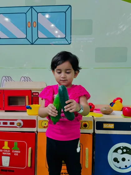 A toddler explores different textures and shapes with our toy vegetables in the pretend kitchen.