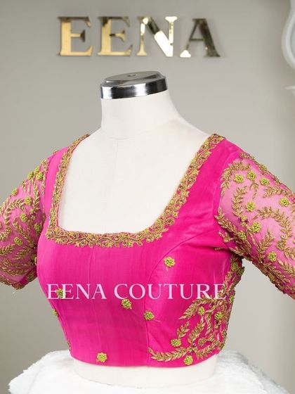 Grace in every detail. This pink net blouse features delicate leafy vines embroidered in gold and light green thread. The deep V-back and sheer sleeves add a touch of modern femininity.