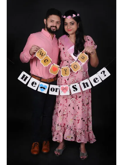 A fun gender reveal photo with a "He or She?" banner. These couple maternity sessions are a wonderful way to capture the anticipation and joy together.