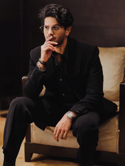 Dulquer Salmaan in a classic all-black suit. This look is about understated luxury, with a focus on the perfect fit and high-quality fabrics from designers like Alexander McQueen and YSL.