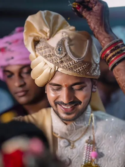 The groom smiles as a ritual is performed, a candid moment filled with warmth and happiness. I focus on capturing the groom's experience and emotions just as much as the bride's.