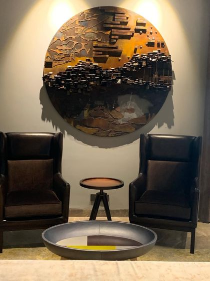 A pair of classic wingback chairs in dark leather create a perfect conversation nook, anchored by a piece of dimensional wall art.