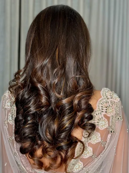 The hairstyle was kept simple and elegant with sleek, open hair and soft curls at the ends, letting the makeup and outfit be the main focus.
