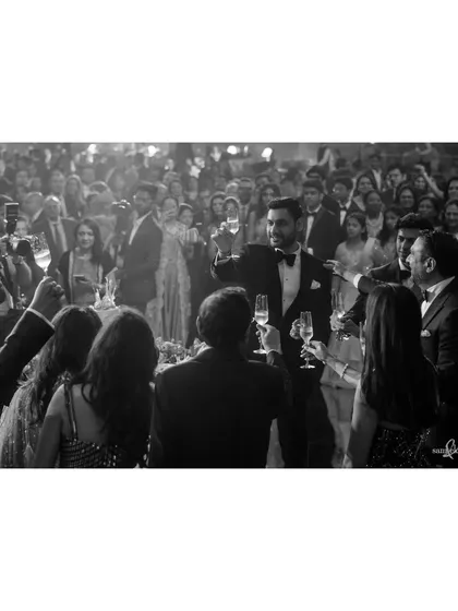 Shivam raises a toast to his and Tanya's families. This black and white photo captures a moment of gratitude and celebration, with the focus on the groom's heartfelt gesture.