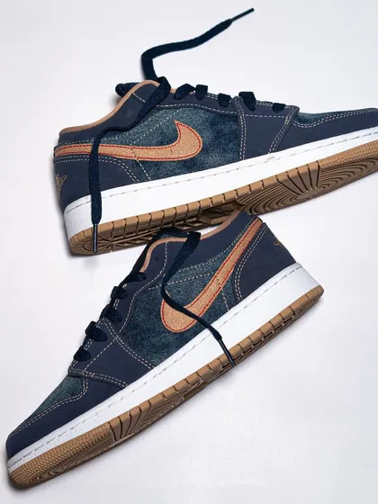 The Air Jordan 1 Low 'Denim' laid out, showcasing the unique washed denim upper and contrasting materials.